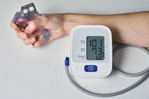 hand with a handful of pills and a digital blood pressure monitor . Healthcare and medicine concept photo