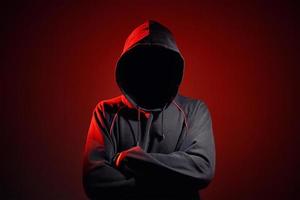 Silhouette af man without face in hood on red background. Anonymous crime photo