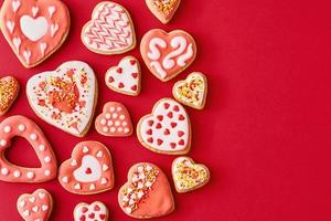 Glazed with icing heart shape cookies on the red backgroundwith copy space. Valentines Day food concept photo