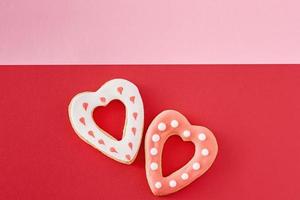 Decorated heart shape cookies on a colored red and pink background, top view photo