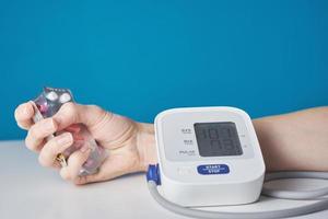 hand with a handful of pills and a digital blood pressure monitor . Healthcare and medicine concept photo