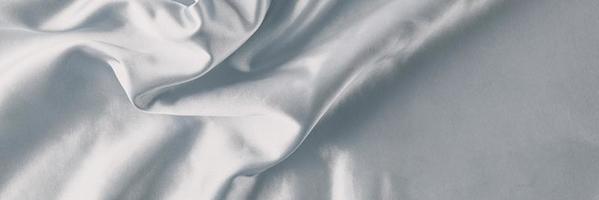 Silver silk background with a folds. Abstract texture of rippled satin surface, long banner