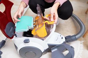 Woman takes out container of dust from vacuum cleaner photo