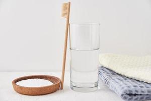 Bamboo toothbrush, baking soda and glass of water on white background photo