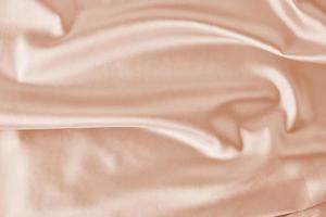 Light pink silk background with a folds. Abstract texture of rippled satin surface photo