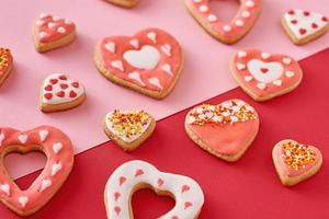 Decorated heart shape cookies on a colored red and pink background, top view photo