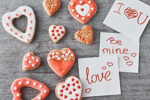 Deocrated heart shape cookies and paper sheets with inscriptions be mine, love and i love you on the gray background. Valentines Day concept photo