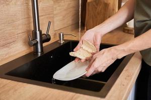 Woman wash dishes with wooden eco friendly brush. Zero waste concept photo