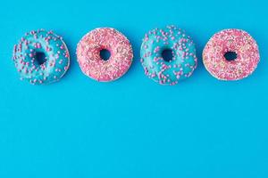 Different types of a colorful donats decorated sprinkles and icing on blue background photo