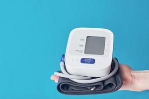 Digital blood pressure on the hand against blue background with copy space. Healthcare and medicine concept photo