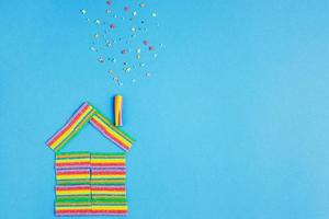 House with pipe made with colorful rainbow candies on the blue background photo