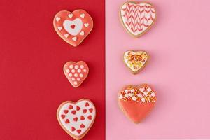 Decorated heart shape cookies on a colored red and pink background, top view photo