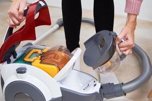 woman take out container of dust from vacuum cleaner photo
