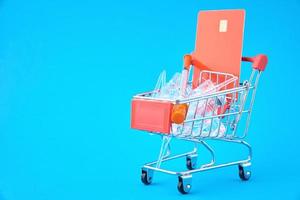 Syringes and ampoules with medicine in shopping cart on blue background photo