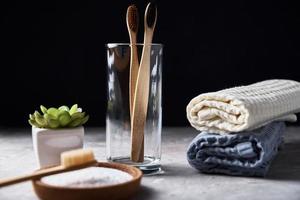 Bamboo toothbrushes in glass and bathroom towels on dark background photo