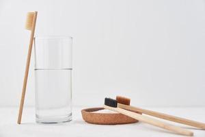 Bamboo toothbrushes, baking soda and glass of water on white background photo