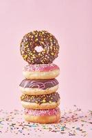 Stack of colorful donuts decorated on a pink background photo