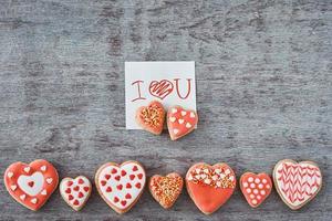 galletas decoradas con forma de corazón y hoja de papel con la inscripción te amo en el fondo gris. concepto del día de san valentín foto