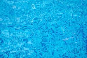 Background of water in blue swimming pool, water surface with a sun reflection photo