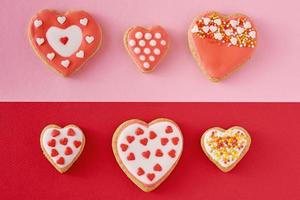 Decorated heart shape cookies on a colored red and pink background, top view photo