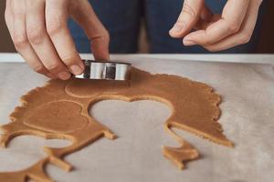 Making gingerbread cookies in the shape of a heart for Valentines Day. Woman hand use cookie cutter. Holiday food concept photo