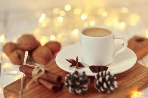 Cozy autumn or winter concept. Cup of coffee with a garland lights and decoration photo