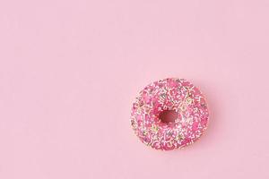 donats decorated sprinkles and icing on a pink background. Creative and minimalis food concept, top view flat lay photo