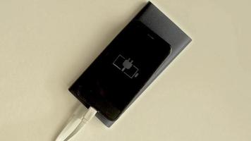 Black smartphone is charging by powerbank ,flashing charging indicator.Top view. video