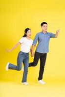 full body image of asian couple posing on yellow background photo