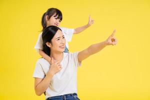 image of asian mother and daughter posing on a yellow background photo