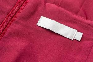 Blank white laundry care clothes label on red fabric texture background photo