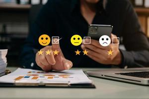 Customer service evaluation concept. woman Show face smile emoticon show on virtual screen from hand.looking at smart phone, tablet and laptop photo