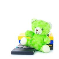 green teddy bear and stack of books on white background photo