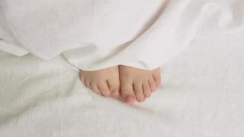 The child moves his legs under the covers. Children's morning. Awakening. Close-up. Video