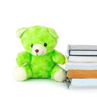 green teddy bear and stack of books on white background photo