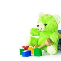 green teddy bear and stack of books on white background photo