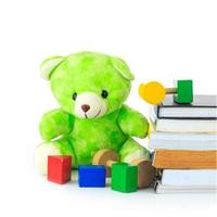 green teddy bear and stack of books on white background photo