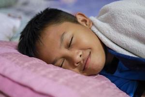 Asian boy is sleeping well on the mattress and blanket in his bedroom. Sweet Dreams photo
