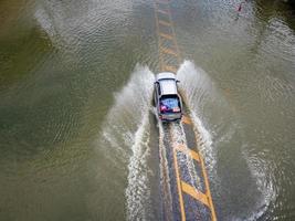 Flooded roads, people with cars running through. Aerial drone photography shows streets flooding and people's cars passing by, splashing water. photo