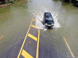 caminos inundados, gente con autos corriendo. la fotografía aérea de drones muestra calles inundadas y autos de personas que pasan, salpicando agua. foto