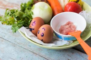 Fresh vegetables, eggs and pork chops. On blue wooden photo