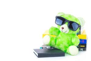 green teddy bear and stack of books on white background photo