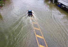 Flooded roads, people with cars running through. Aerial drone photography shows streets flooding and people's cars passing by, splashing water. photo