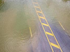 Flooded roads, people with cars running through. Aerial drone photography shows streets flooding and people's cars passing by, splashing water. photo