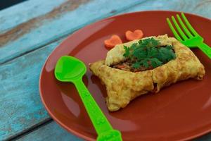 stuffed omelette, Omelet with vegetable salad and Heart-shaped carrot, on blue old wooden photo