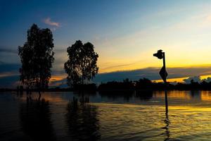 The silhouette of a traffic light on a street flooded at sunset. photo