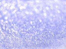 Inspired by trendy very peri color of the year 2022. Abstract blurred light violet sparkling bokeh. Shiny snow texture on a winter sunny day. Christmas and New Year background. Place for text.