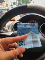 A hand is holding a fifty thousand rupiah bill which bends while driving. photo