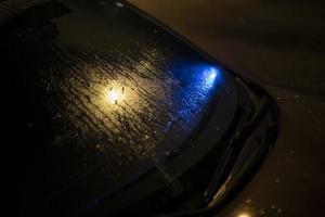 Blue signal under car glass. Signal light under wet window. Details of transport at night. photo