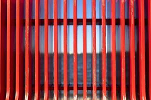 Red texture on background of sea. Details of bench on embankment. Red vertical lines. photo